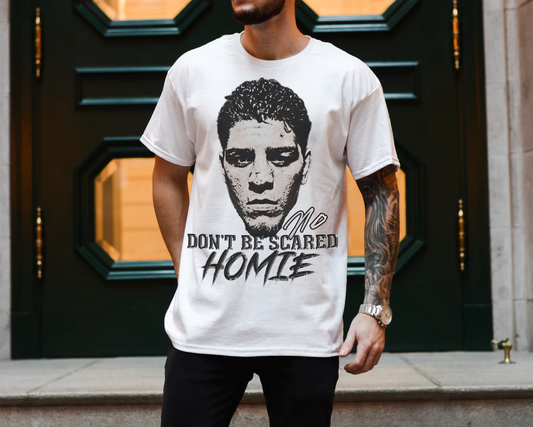 Front view image: Alt text: Front view of the Kings Origin Nick Diaz “Don’t Be Scared Homie” heavyweight black t-shirt.
Detail image: Alt text: Close-up of the big-face graphic on the Kings Origin Nick Diaz t-shirt.
Model image: Alt text: Male model wearing the Kings Origin Nick Diaz t-shirt.